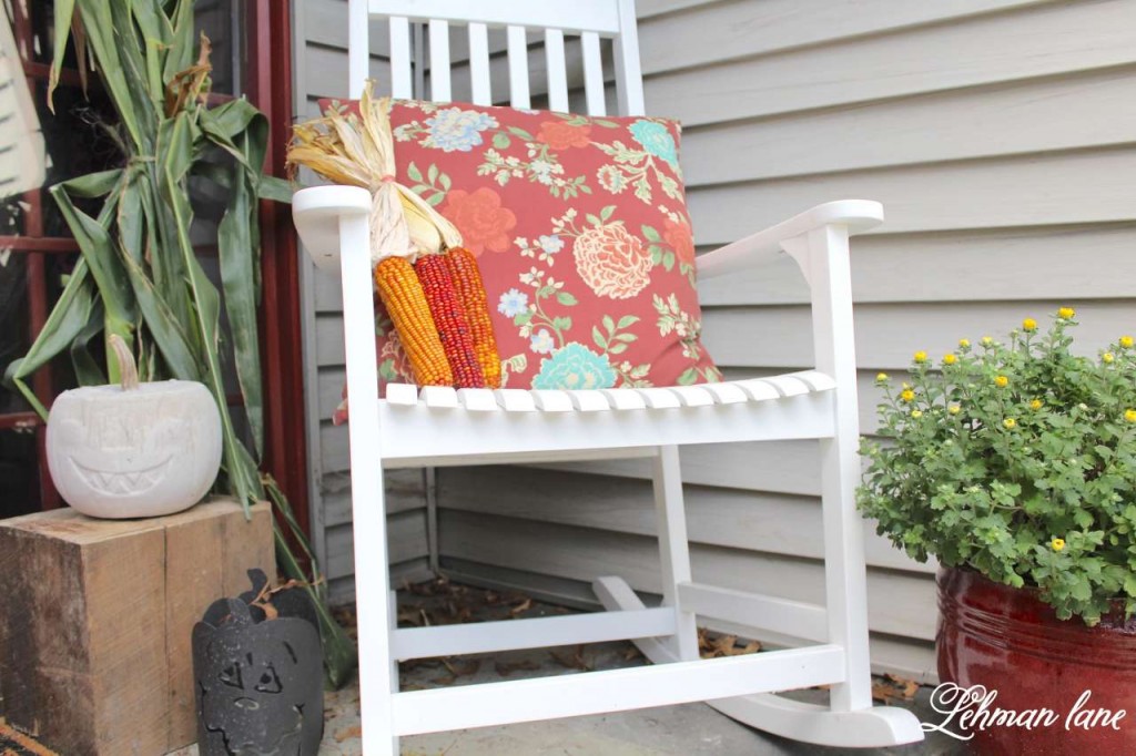 Fall front porch - white rocking chair, concrete pumpkin, mums