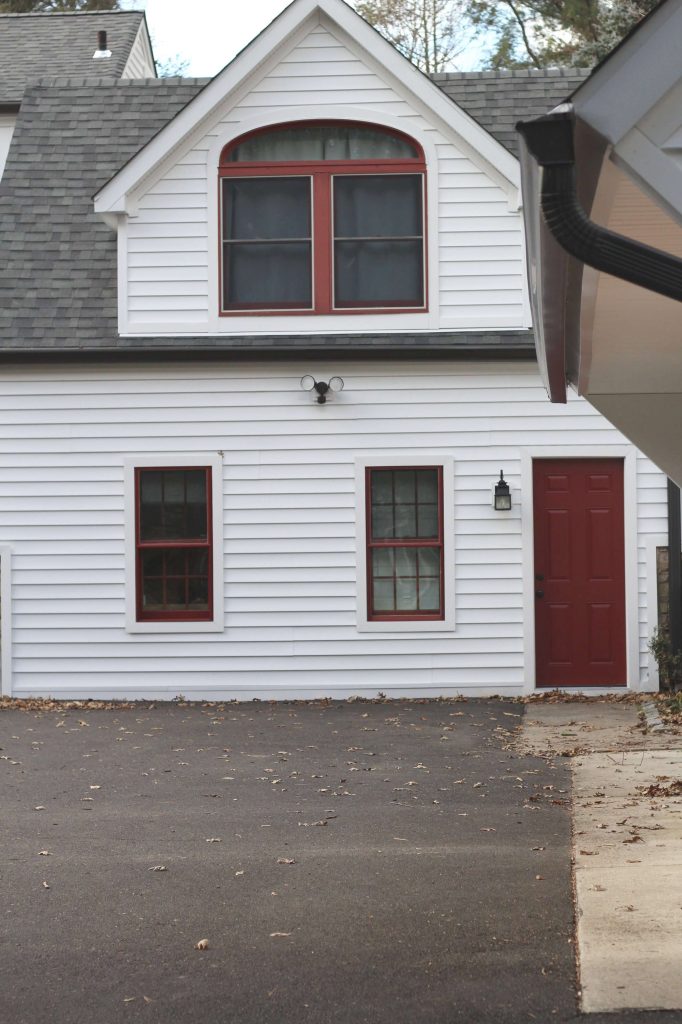 Sharing all our tips & tricks for how to make vinyl siding look BETTER with before & after pictures of our beautiful white farmhouse with red windows & doors & white PVC trim. #whitefarmhouse #farmhousecurbappeal https://lehmanlane.net